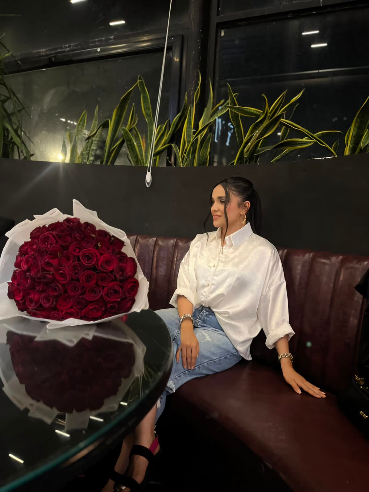 Zahra seated beside a large bouquet of red roses
