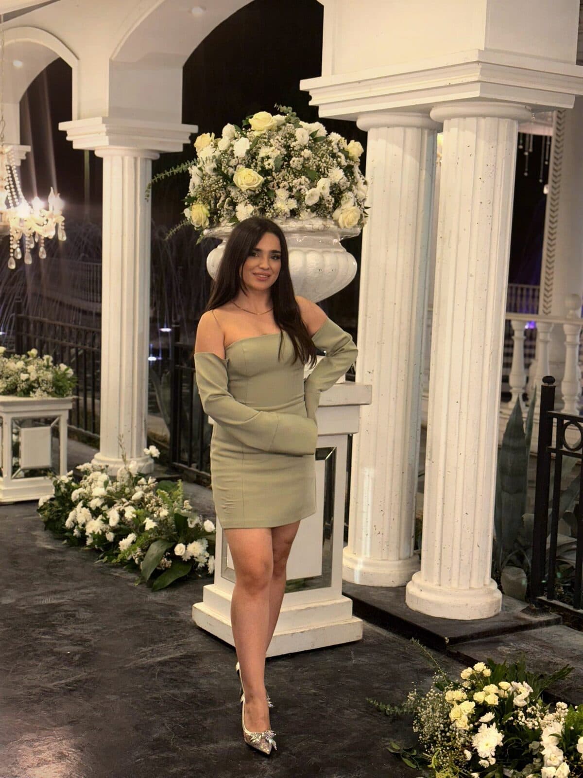 Zahra standing between white columns beside a floral urn