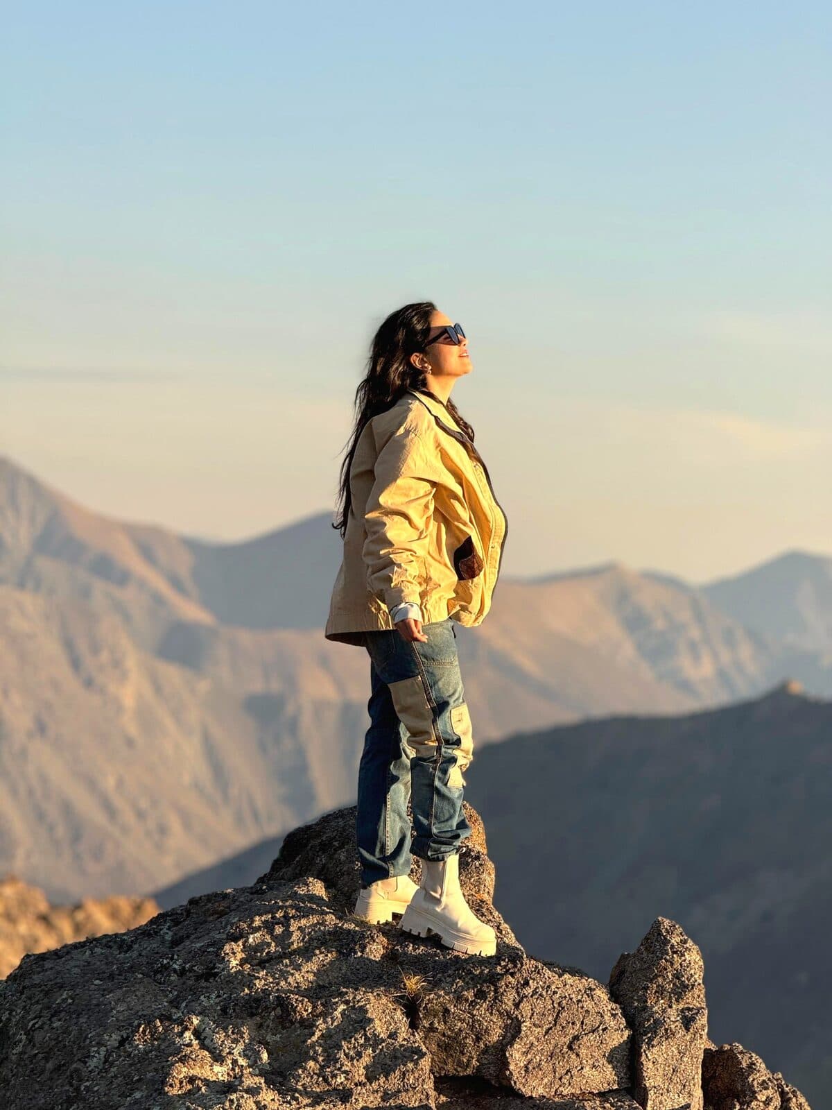 Zahra Aghaei standing on a mountain summit at sunset